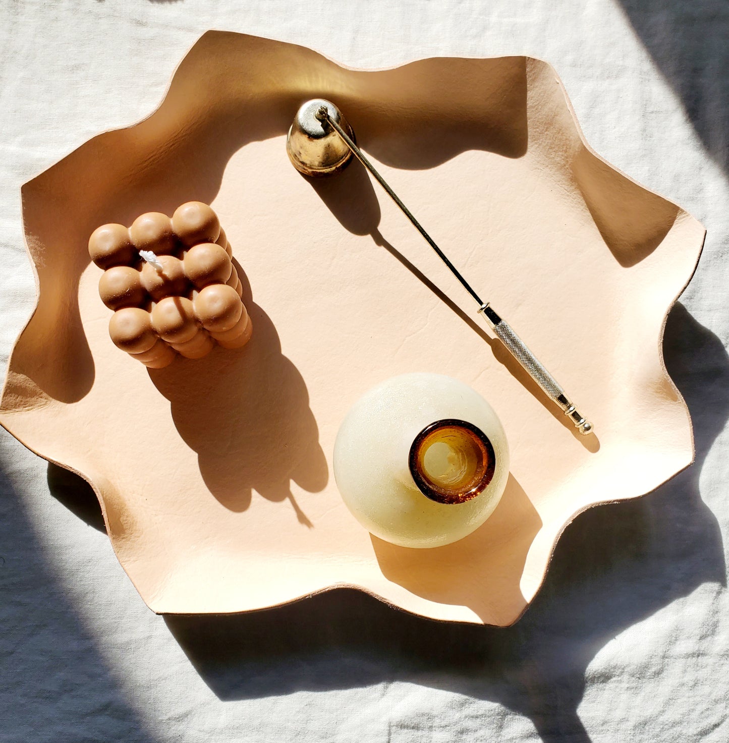 Leather wavy bowl with a candle & bud vase & candle sniffer on it. Handmade in Los Angeles, California