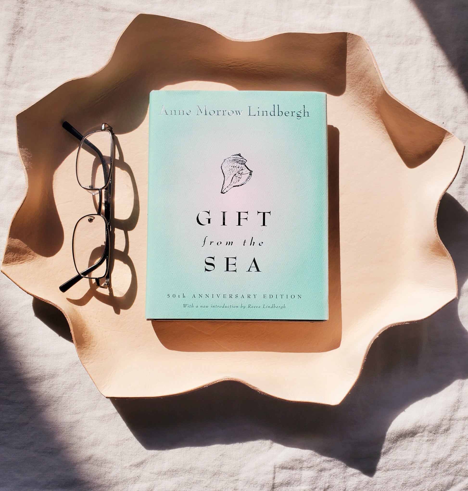 Leather wavy bowl with a book & glasses in it. Handmade in Los Angeles