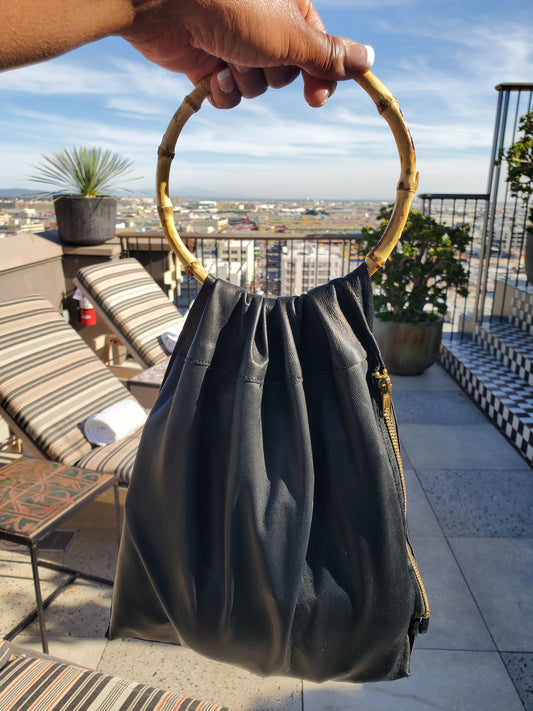 Black leather bag with a bamboo handle & side zipper. Made in Los Angeles California. 