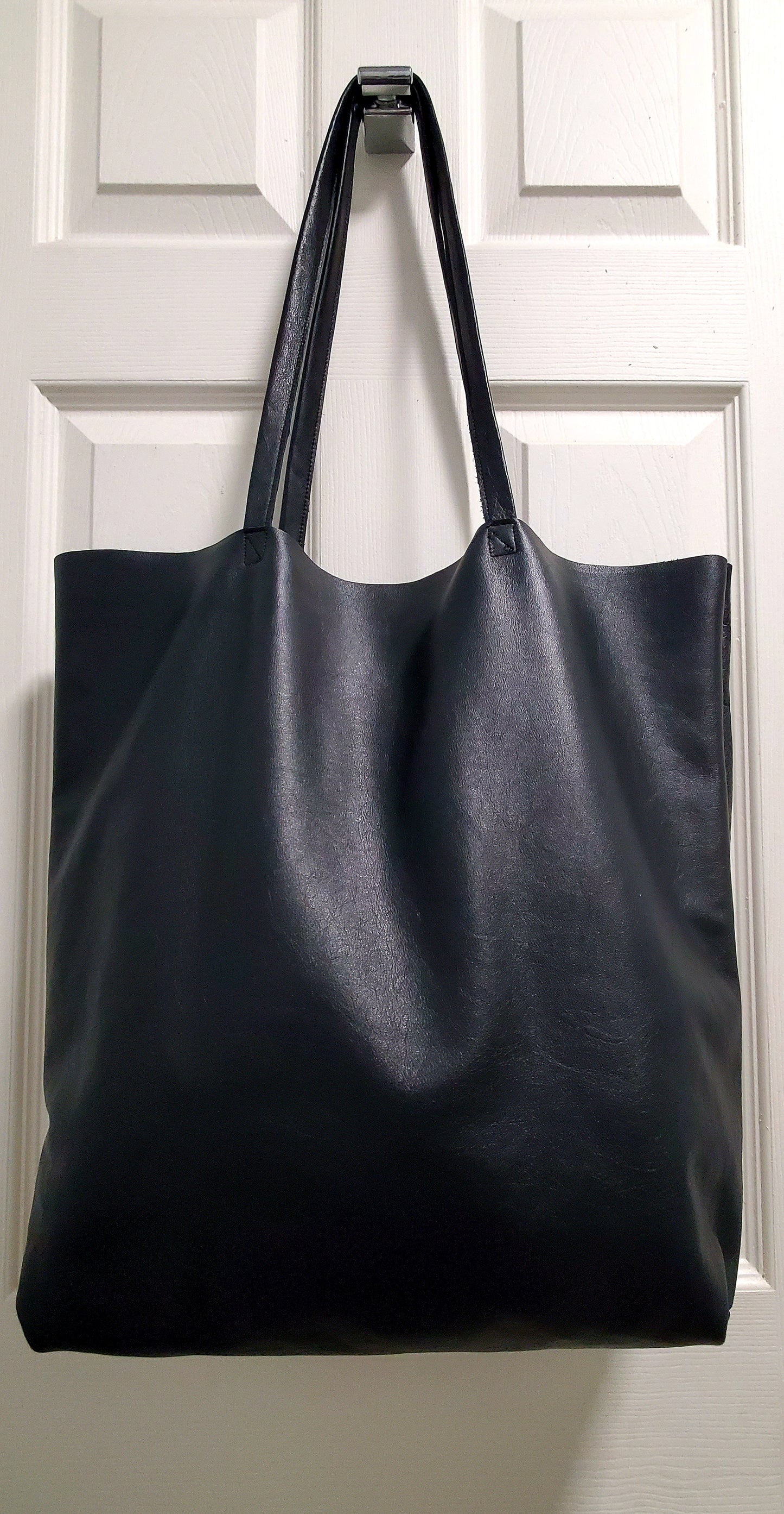 Black leather tote bag with 2 inside pockets. Perfect for cellphone & glasses.